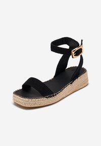 Sandale espadrille noire avec deux brides en tissu, une semelle plateforme en jute tressé et un accent en boucle dorée sur la bride de la cheville.