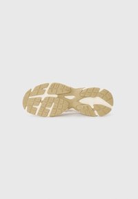 Rubber sneaker sole in beige with textured patterns and grooves for traction. Features athletic design and cushioning elements.