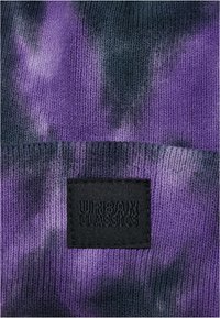 Berretto a maglia con un motivo tie-dye viola e nero, con una superficie testurizzata e un'etichetta nera incisa con "URBAN CLASSICS."
