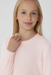 Helles rosafarbenes, flauschiges Sweatshirt mit Rundhalsausschnitt und langen Ärmeln. Weiche Textur, gerippte Bündchen und Kragen. Einfaches, gemütliches Design.