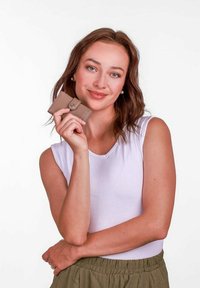 Béžová kožená peněženka se snap uzávěrem, kterou drží modelka v bílém topu bez rukávů, představující hladkou texturu a kompaktní design.