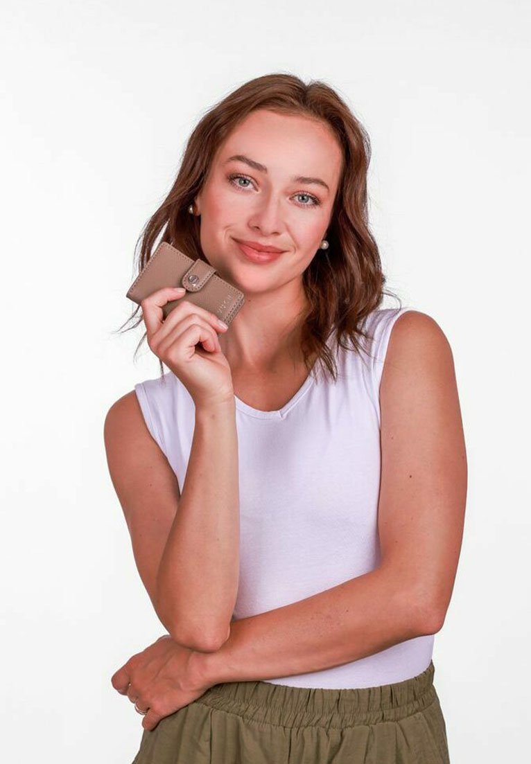 Béžová kožená peněženka se snap uzávěrem, kterou drží modelka v bílém topu bez rukávů, představující hladkou texturu a kompaktní design.