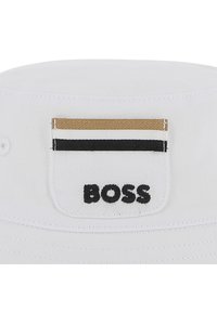 Bijela kanta kapa od pamuka, s prednjom zakrpom s crnim, zlatnim i bijelim prugama te izvezenim natpisom "BOSS" u crnoj boji.