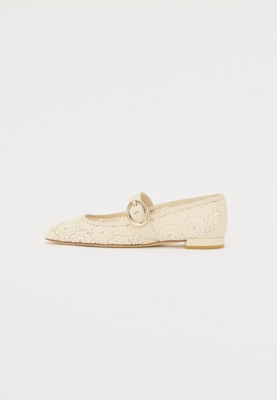 Ballerines en dentelle beige avec un bout pointu, un revêtement en dentelle et une lanière latérale ornée d'une boucle ronde en or. Talon plat et doublure intérieure lisse.