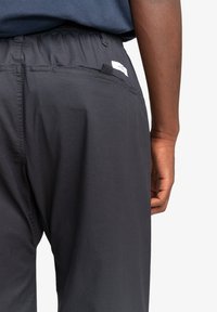 Zwarte, lichte shorts met een elastische tailleband. Bevat een achterzak met een klein lusje en een gladde stoftextuur.