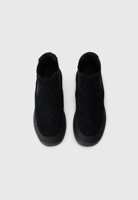 Botines de ante negro con un acabado texturizado, que presentan una punta redonda y suela de goma, diseñados para un fácil calzado.