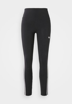 Leggings negros hechos de material elástico, con una cinturilla alta y franjas laterales blancas. Pequeño logo cerca de la cintura en la parte delantera.