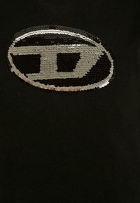 T-shirt in tessuto nero con un grande design ovale realizzato in paillettes nere e argentate. Le paillettes creano una superficie riflettente e strutturata.