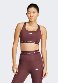 Bordeaux sport-beha met brede banden en een wit logo, gecombineerd met bijpassende high-waisted leggings met een gebrandmerkte tailleband en een slim fit.