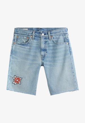 Ljust blå denimshorts med fransade fållar, fem fickor, knappstängning och en röd och vit blomstertäckning på vänster ben.