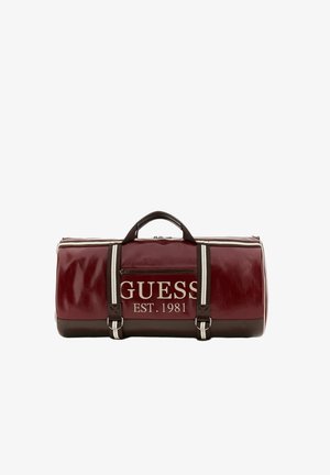 Bordeauxroter und brauner zylindrischer Duffelbag mit weiß gestreiften Griffen und "GUESS EST. 1981" auf der Vordertasche.