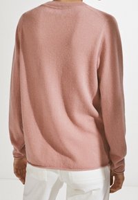 Różowy sweter z długim rękawem wykonany z miękkiego, fakturowanego materiału, z zaokrąglonym dekoltem i luźnym krojem z tyłu.
