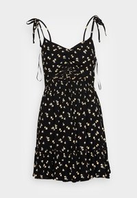 Vestido negro de flores con tirantes ajustables, un cuerpo fruncido y un dobladillo con volantes decorado con pequeños patrones de flores amarillas y blancas.