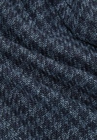 Tissu tricoté bleu foncé et gris montrant une texture côtelée détaillée et de doux plis.