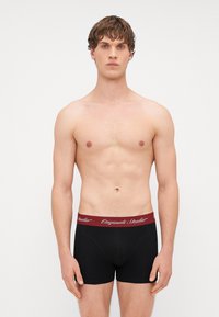 Boxers noirs avec une ceinture élastique bordeaux portant un texte blanc. Texture lisse, design ajusté, longueur mi-cuisse.
