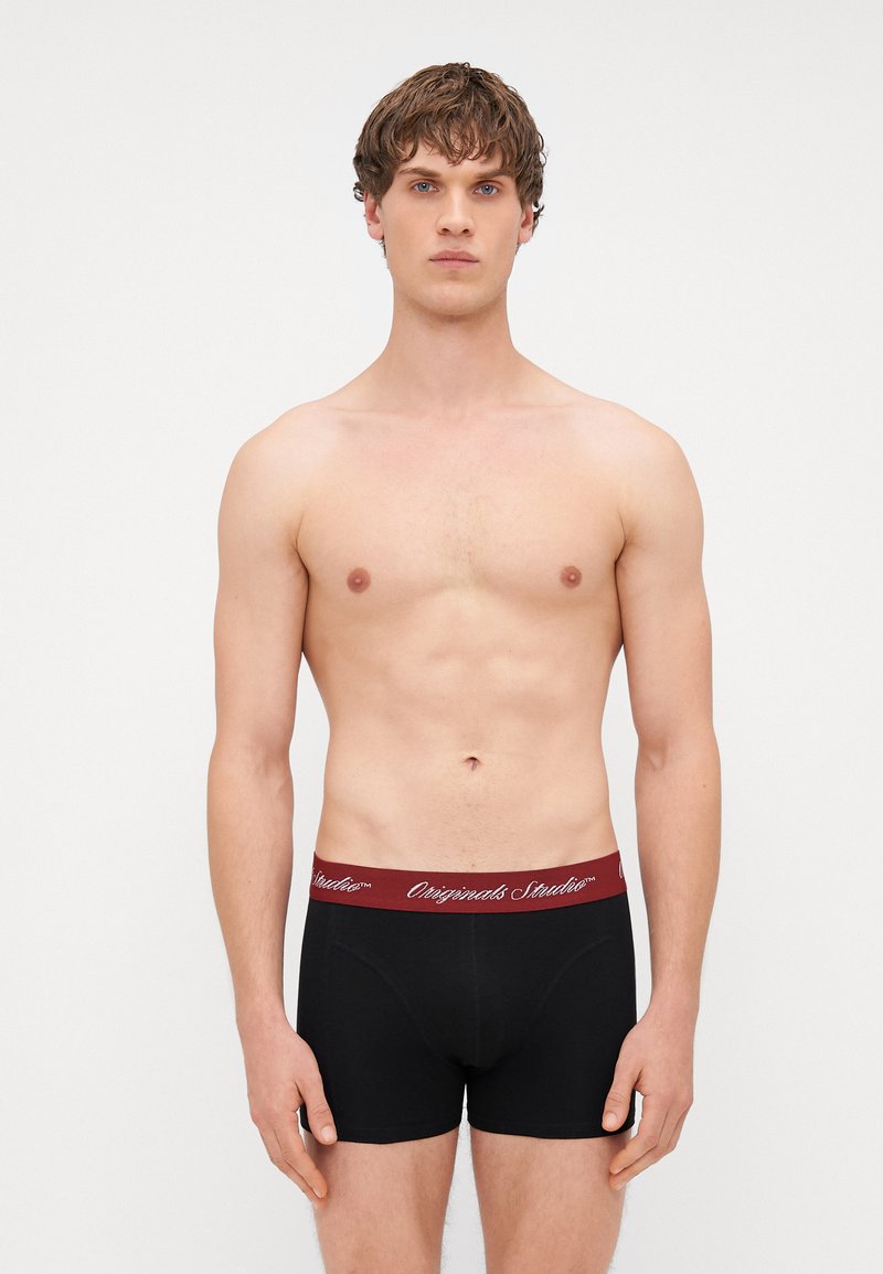 Mustad mustad boksershorts burgundi elastse vööga, millel on valge tekst. Sile tekstuur, kaalutud disain, reie keskmine pikkus.