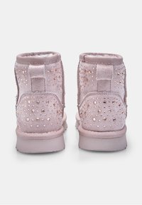 Pár svetloružových zamkových búnd so zdobením z rhinestones na zadnej strane, ploché podrážky a polstrované golieriky, pohľad zozadu.