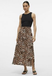 Top nero abbinato a una maxi gonna con stampa leopardata, dotata di uno spacco frontale, realizzata in tessuto morbido con una superficie liscia.