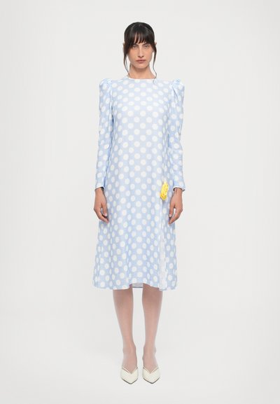 Hellblaues Polka-Dot-Kleid mit langen Ärmeln, Puffschultern und knielangem Saum. Mit einem gelben Akzent an der Taille. Strukturiertes Material.