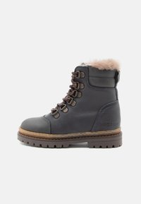 Botte en cuir bleu foncé avec un col en fausse fourrure, des œillets en métal et des lacets marron. Semelle texturée, design robuste et logo embossé sur le talon.