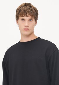 Zwarte sweatshirt van Calvin Klein, gemaakt van zachte stof, met een ronde hals, een losse pasvorm en een ingebosseld logo op de borst.