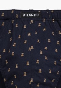 Granatowe szorty z materiału z powtarzającym się wzorem małych brązowych misiów. Elastyczny pasek w talii z widoczną metką "ATLANTIC".