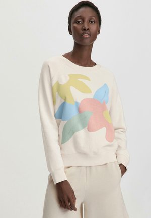 Sudadera de color beige claro con un gráfico floral en rosa, azul, verde y amarillo. Presenta puños y dobladillo acanalados. Diseñada con un corte relajado.