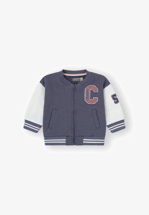 Chaqueta bomber de navy con cremallera y mangas blancas, puños a rayas y parches. Material suave, dos bolsillos frontales, cuello y dobladillo acanalados.