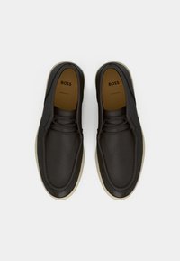 Σκούρα καφέ δερμάτινα παπούτσια με απαλή υφή, διακριτικό ράψιμο, στρογγυλεμένη μύτη και ελαφριά κρεμ σόλα. Το λογότυπο BOSS είναι ορατό στο εσωτερικό.
