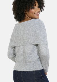 Gray knitted sweater with a ribbed off-shoulder design, featuring a soft texture and subtle shimmer. Fitted at the waist with long sleeves.
