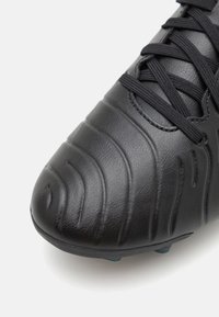 Black soccer cleat with a smooth leather upper featuring raised wave patterns, flat laces, and a rounded toe. Includes a textured finish.