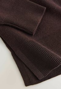Dark brown knitted sweater featuring ribbed cuffs and hem, showcasing a textured finish with varying knit patterns throughout.