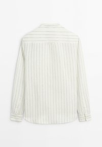 Chemise blanche à manches longues avec fines rayures verticales noires, poignets boutonnés et un empiècement avec des rayures horizontales sur le haut du dos.