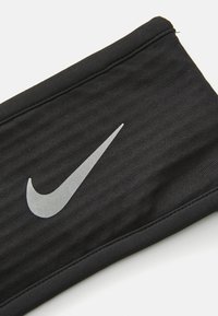 Un bandeau de sport noir en tissu texturé, arborant un logo Nike en argent bien en vue. Les bords sont cousus pour une durabilité accrue.