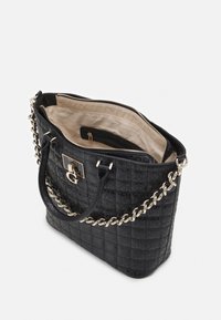 Černá prošívaná kabelka vyrobená z umělé kůže s zlatým řetízkovým popruhem, obsahující zipové zavírání a béžově podšívku uvnitř.