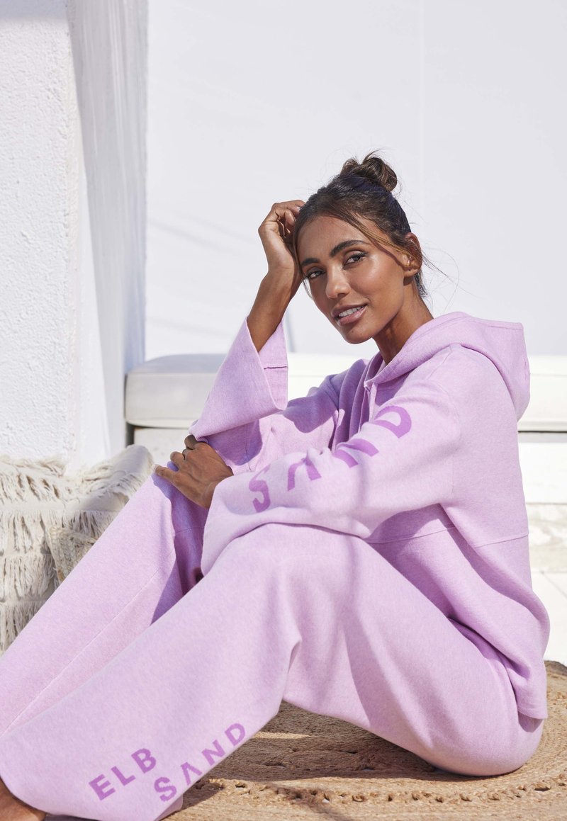 Felpa oversized viola chiaro e jogger coordinati realizzati in morbido tessuto, con la scritta "ELB SAND" sulle maniche e sui pantaloni.