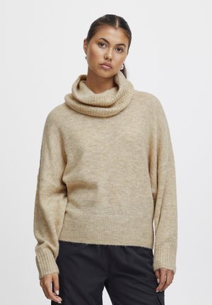 Beige coltrui met een zachte, textuurrijke afwerking. Heeft ribgebreide manchetten en zoom, een ontspannen pasvorm en licht oversized mouwen.