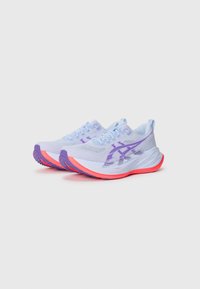 Zapatillas de correr azul claro con acentos morados, parte superior de malla texturizada y suela rosa. Logo notable y patrón de goma duradero en la suela.