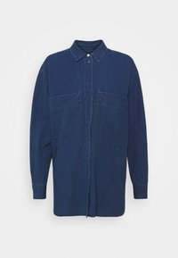 Chemise en denim bleu foncé avec un col pointu, un fermeture à boutons, des manches longues et deux poches avant. Texture lisse avec une coupe décontractée.