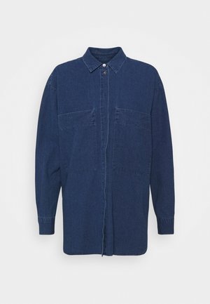 Chemise en denim bleu foncé avec un col pointu, un fermeture à boutons, des manches longues et deux poches avant. Texture lisse avec une coupe décontractée.