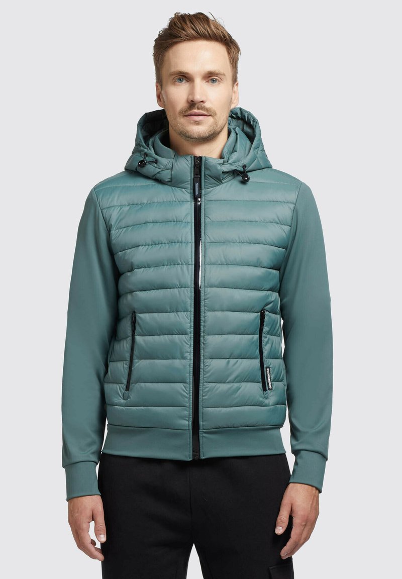  gepolsterte Jacke in Teal mit einem Reißverschluss vorne, verstellbare Kapuze und schwarzen Reißverschlusstaschen. Glatte Textur und taillierte Passform.