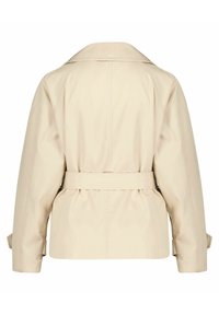 Beżowy trencz z szerokim kołnierzem, paskiem w talii i luźnym krojem. Ma długie rękawy z mankietami na guziki i gładką fakturę.