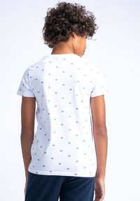 Biała koszulka z krótkim rękawem z małymi zielonymi wzorami słońca. Wykonana z miękkiej bawełny, z okrągłym dekoltem, pokazująca widok z tyłu.