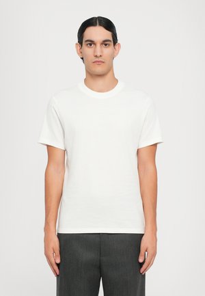 T-shirt en coton blanc avec un col rond et des manches courtes ; texture lisse, design minimaliste et marquage subtil à l'avant.