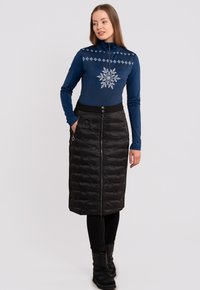 Camiseta de manga larga azul marino con diseño de copos de nieve, combinada con una falda acolchada negra con cremallera frontal y dos bolsillos laterales.