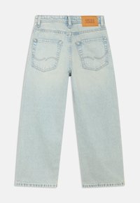 Světle modré džíny z denimu se střihem rovného střihu, s dvěma zadními kapsami, viditelným stehováním a hnědou koženou nášivkou s logem.