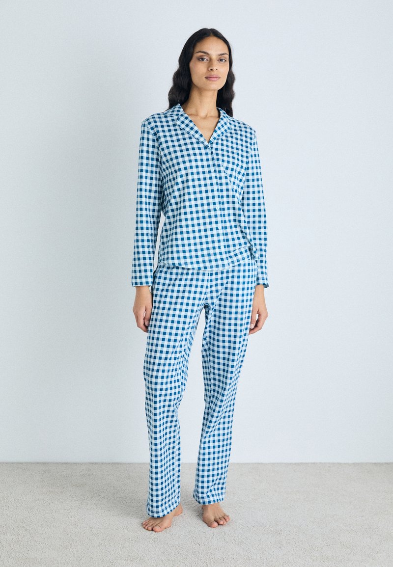 Conjunto de pijama em azul e branco com padrão xadrez, feito de tecido leve, apresentando uma camisa de botão com colarinho e calças de perna reta a condizer.