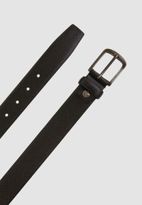 Cintura in pelle nera con una texture traforata, caratterizzata da una fibbia in metallo color argento e diversi fori di regolazione lungo la cinghia.