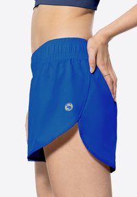Pantaloni corti sportivi blu con un elastico in vita, orlo curvo e un piccolo logo. Tessuto liscio con una sensazione di leggerezza.