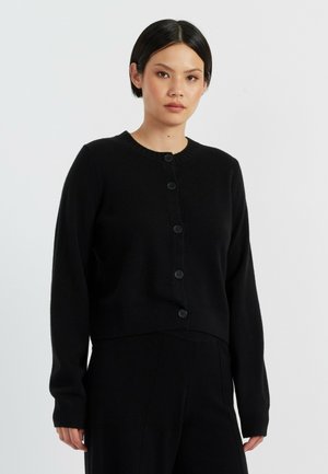 Zwarte cropped cardigan van zachte brei stof, met een ronde halslijn, lange mouwen en zes knopen aan de voorkant. Klassiek ontwerp en pasvorm.